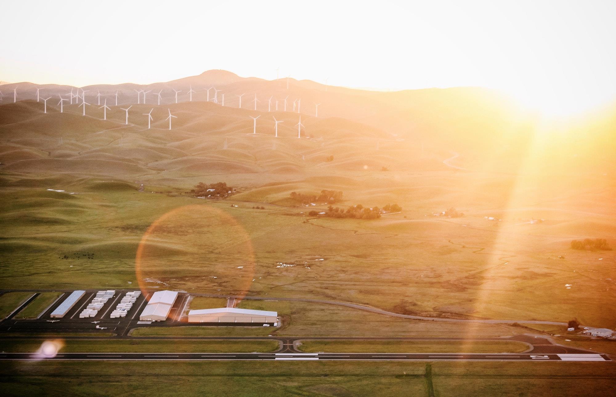 Green field with windmills and sunset